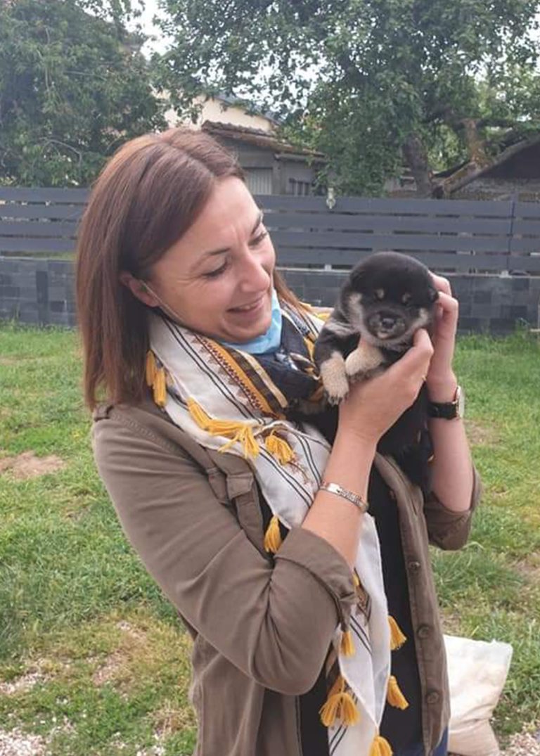Adoptante tenant un chiot Shiba Inu noir et feu au Royaume d'Akuma